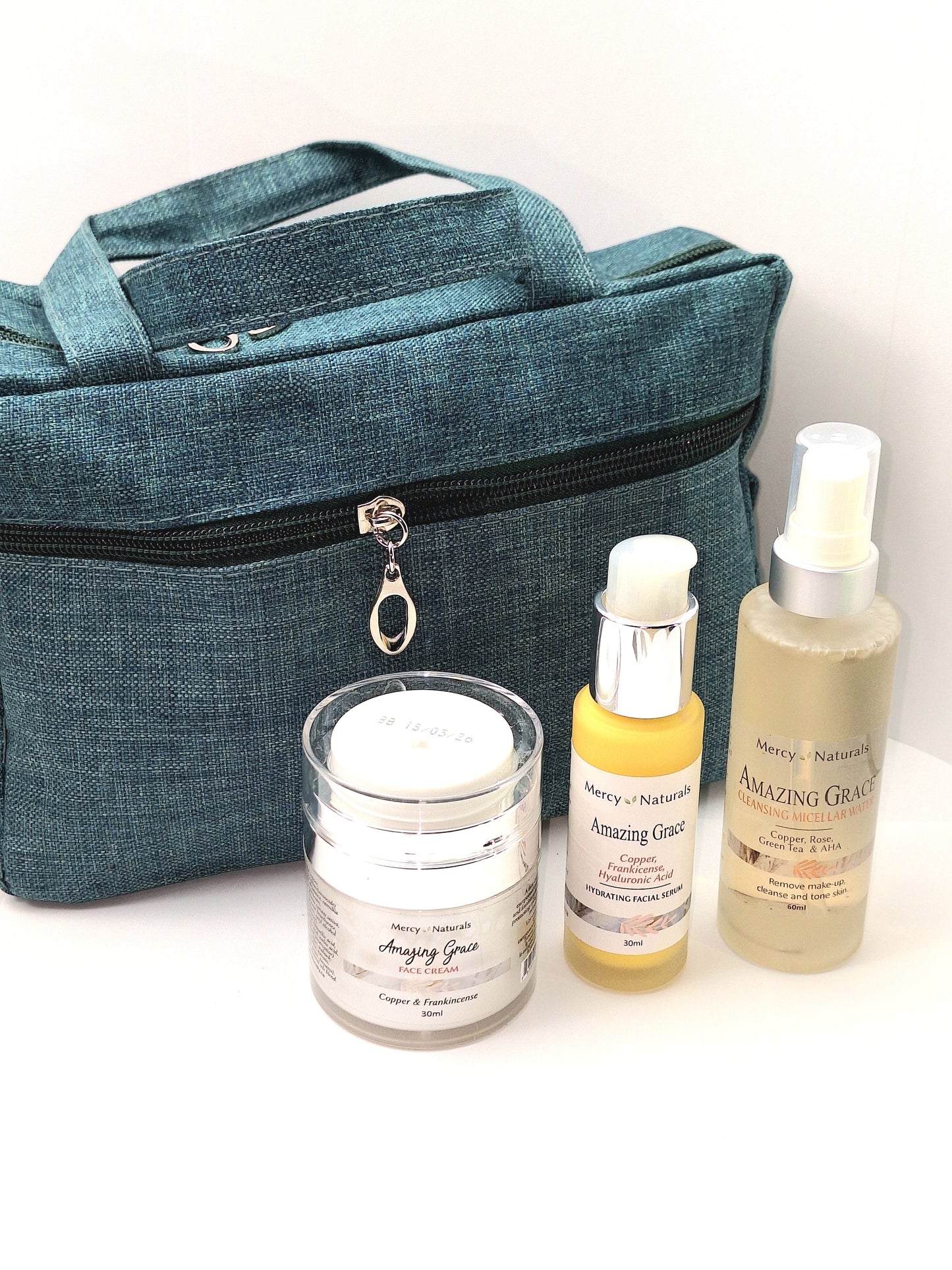 Amazing Grace Set white plastic 30ml push top with clear lid of face cream, 30 ml clear glass stubby with a pump top, 60ml clear glass micellar water with a white spray top with clear lid. green make up bag with zipper top.