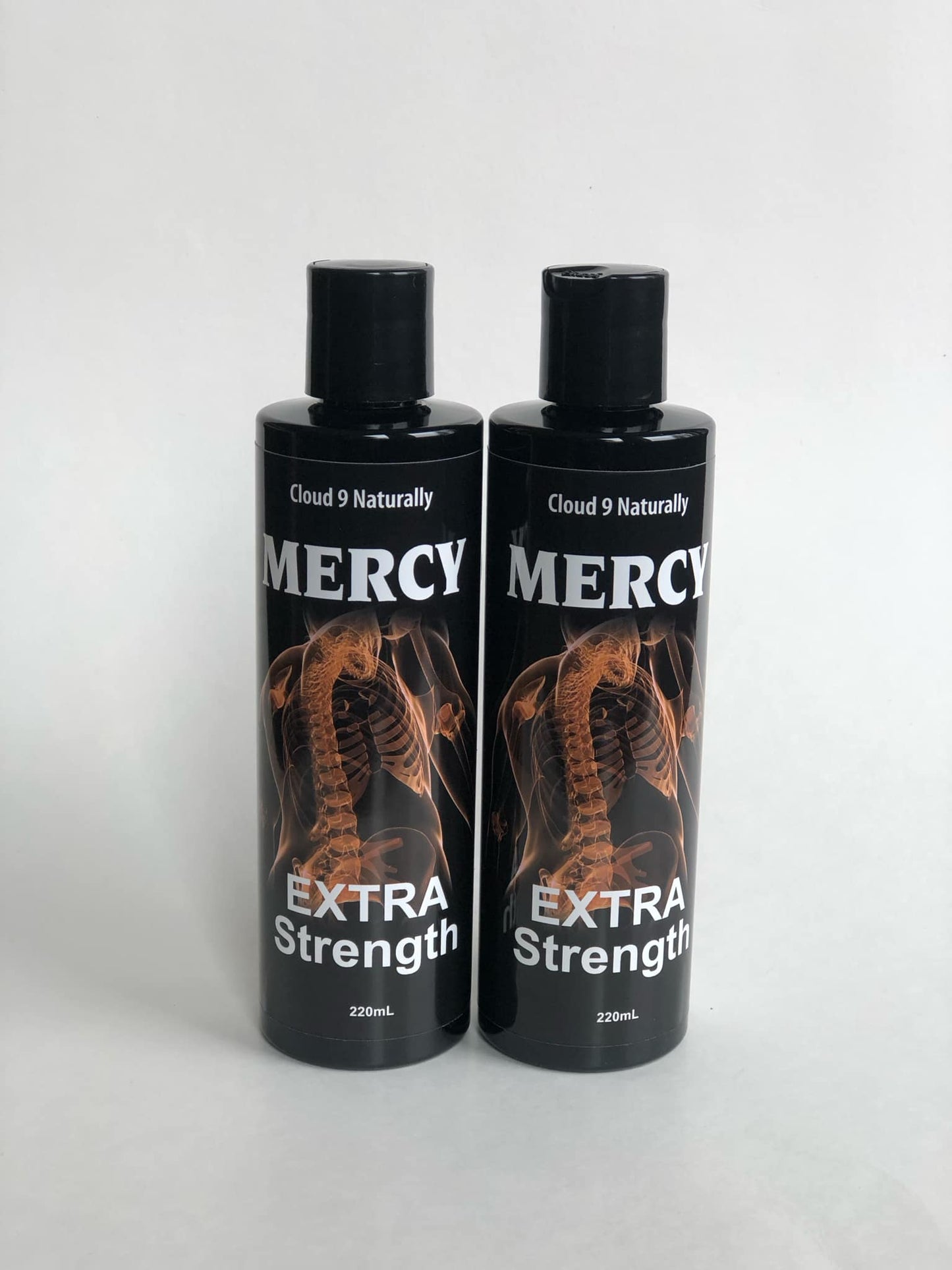 2 Mercy Extra strength 220ml black plastic bottles with flip tops, label has a picture of an orange colored spine skelaton with white lettering.