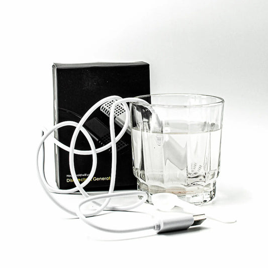 A white portable hypochlorous acid maker is shown with its black retail box, a clear glass of water, and a coiled white cord on a white background.