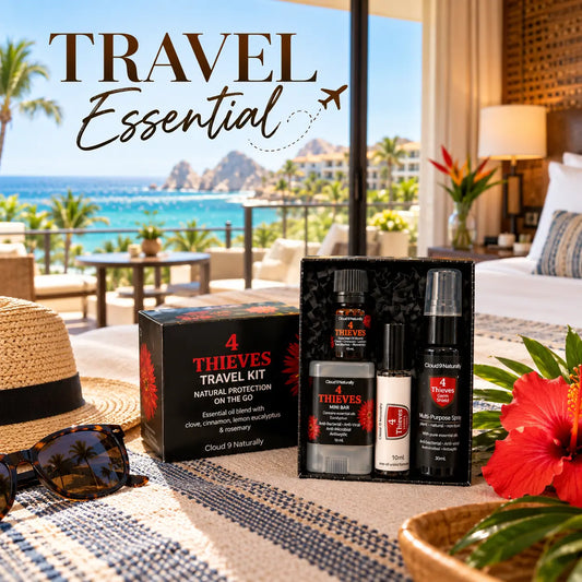 A travel essential protection kit by Cloud 9 Naturally branded, displayed in a black gift box on a beachfront patio. The kit includes a black box, an essential oil blend bottle, a small white bottle, and a multi-purpose spray.