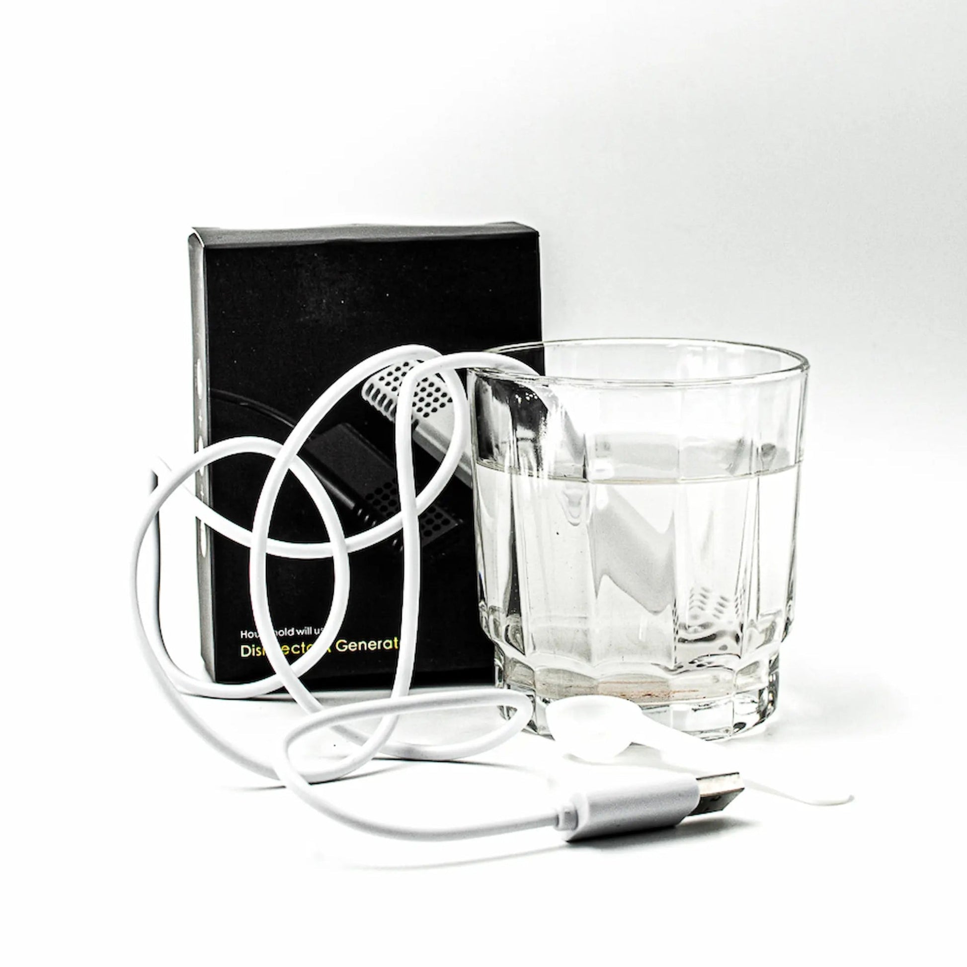 A white portable hypochlorous acid maker is shown with its black retail box, a clear glass of water, and a coiled white cord on a white background.