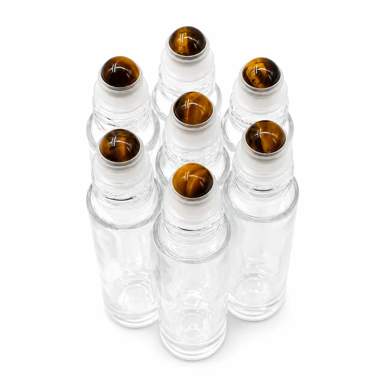 Six clear glass roller bottles with round amber-brown tiger's eye gemstone tops, arranged in a cluster on a white background.